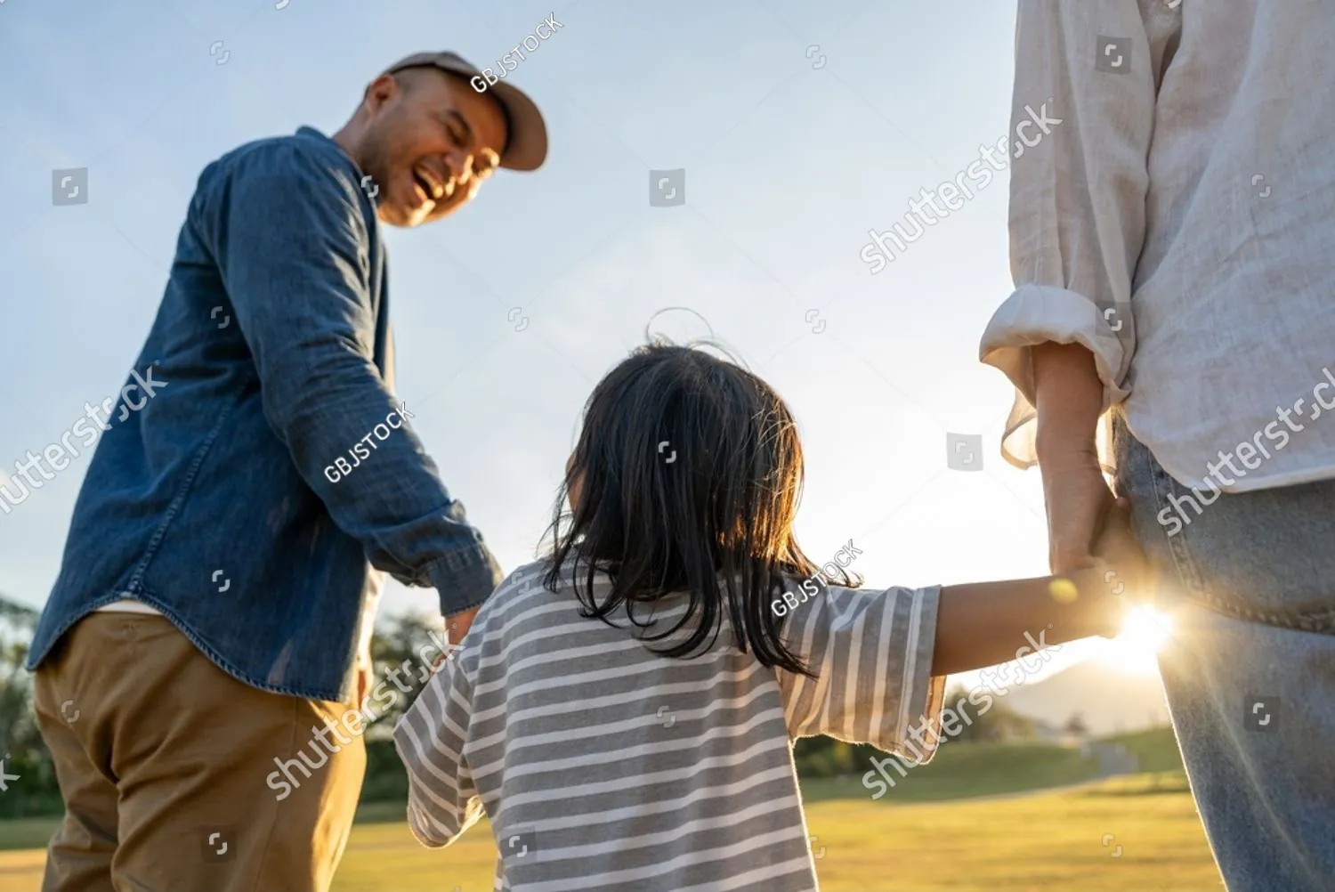 A father walking hand in hand with his young child at sunset